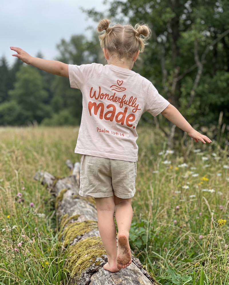 Kleines Mädchen balanciert auf einem Baumstamm, rosa T-Shirt mit Rückenprint Wonderfully made