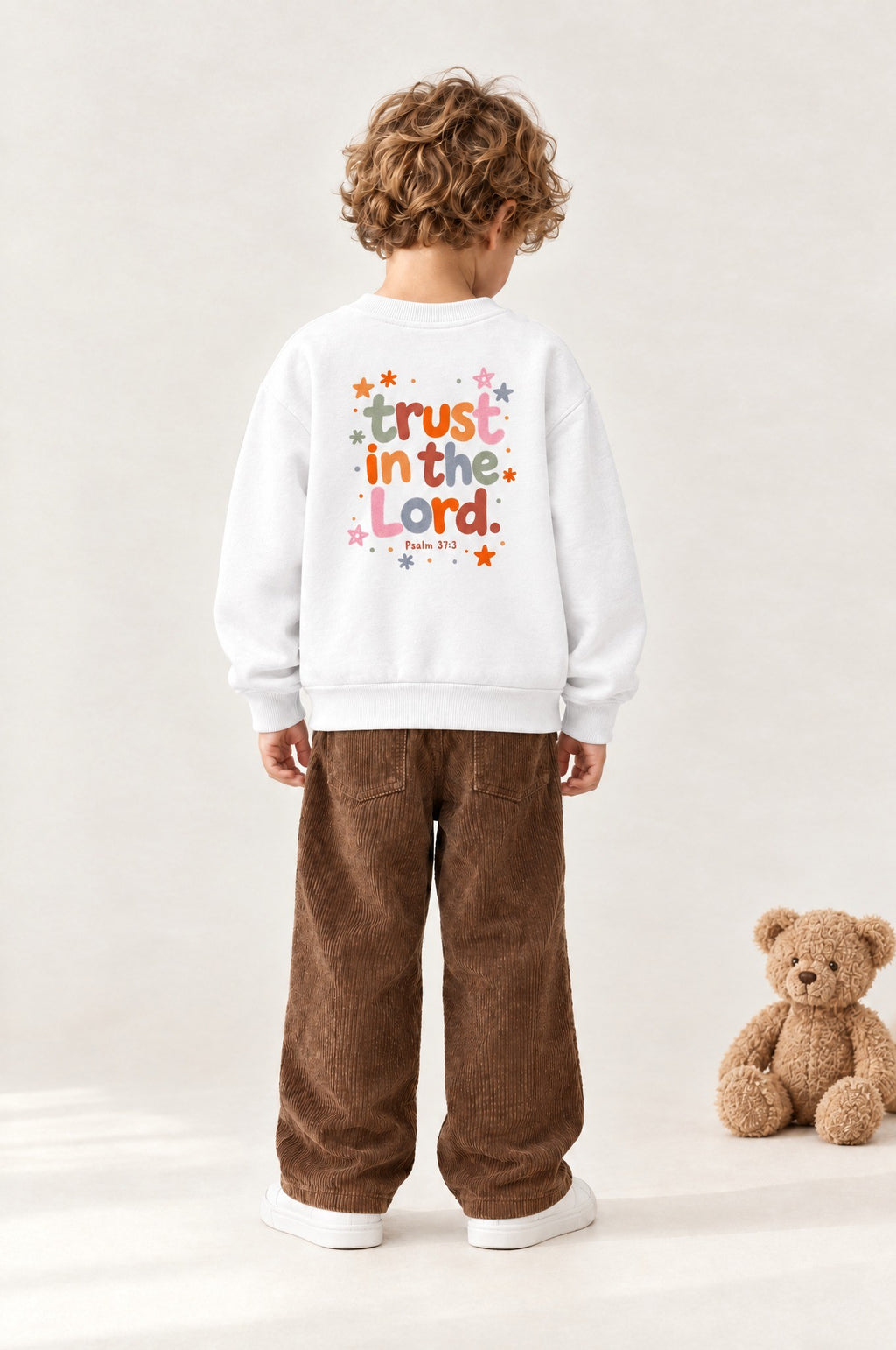 Kind von hinten im Kinder-Sweater „Trust in the Lord“ in Weiß