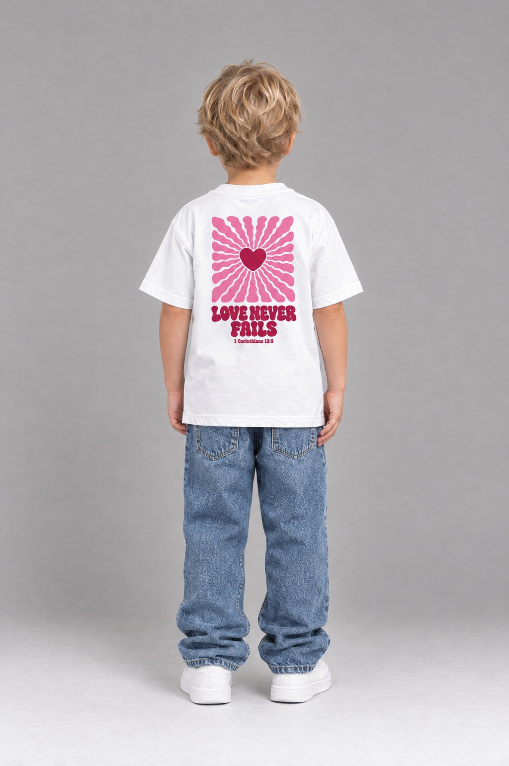 Kind trägt das weiße Kinder T-Shirt „Love never fails (Strahlen)“ von Little Faith