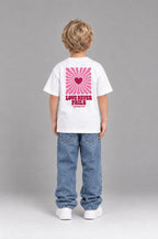 Kind trägt das weiße Kinder T-Shirt „Love never fails (Strahlen)“ von Little Faith