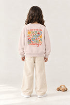 Kind von hinten im Kinder-Sweater „Rejoice in the Lord always“ in Rosa