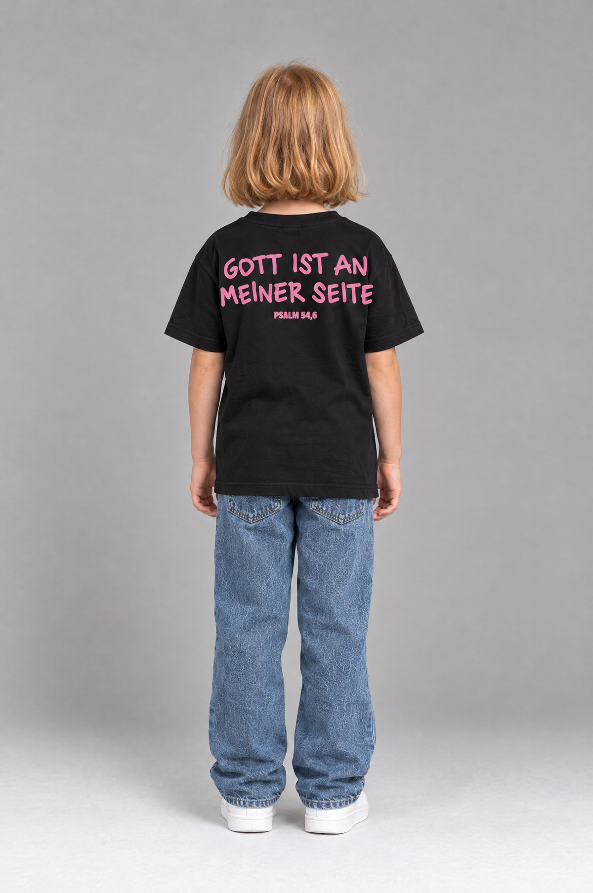 Kind trägt das schwarze Kinder T-Shirt „Gott ist an meiner Seite“ von Little Faith