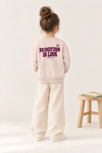 Kind von hinten im Kinder-Sweater Do everything in love in Rosa
