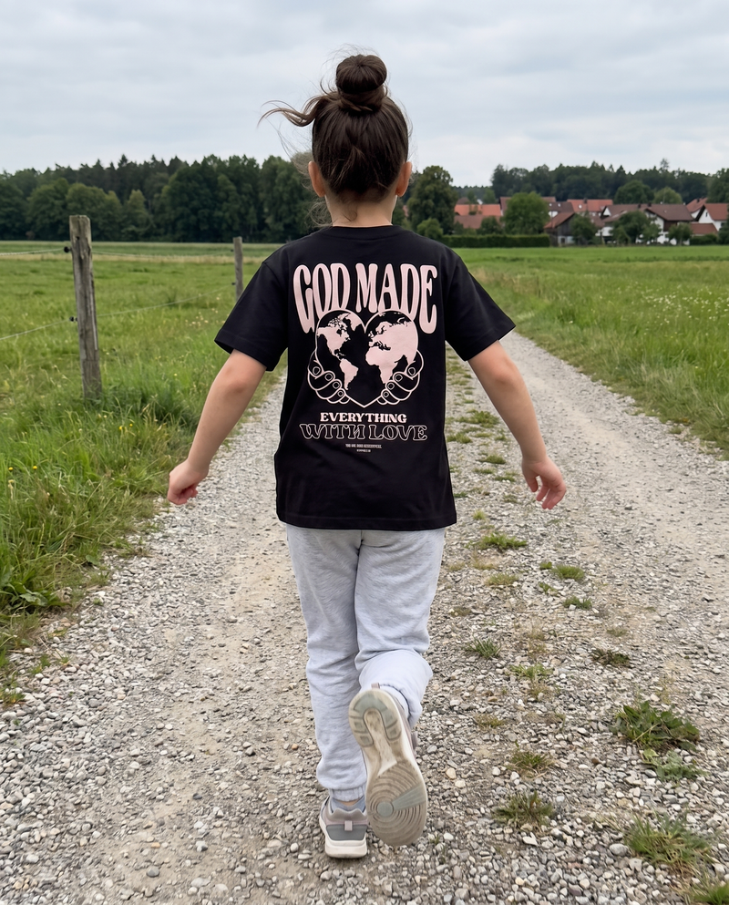 Mädchen läuft einen Feldweg entlang, schwarzes T-Shirt mit Rückenprint God made